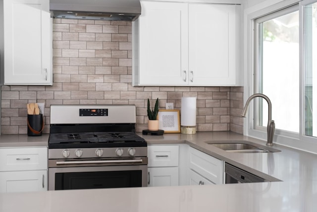 kitchen with stainless steel gas stove, sink, tasteful backsplash, and white cabinetry