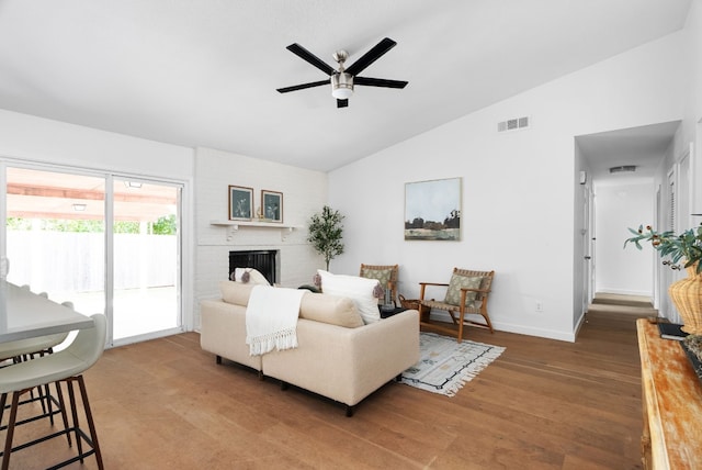 living room featuring a brick fireplace, lofted ceiling, hardwood / wood-style floors, and ceiling fan