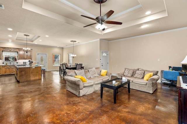 living room with crown molding, ceiling fan with notable chandelier, and a tray ceiling