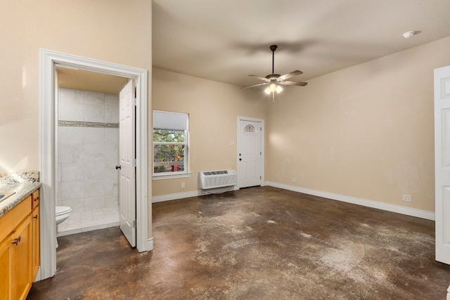 interior space with an AC wall unit, ensuite bath, and ceiling fan