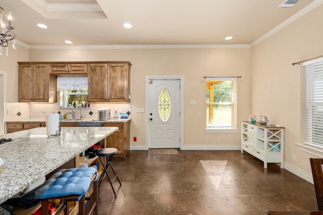 kitchen with decorative backsplash, a wealth of natural light, a kitchen bar, and light stone countertops