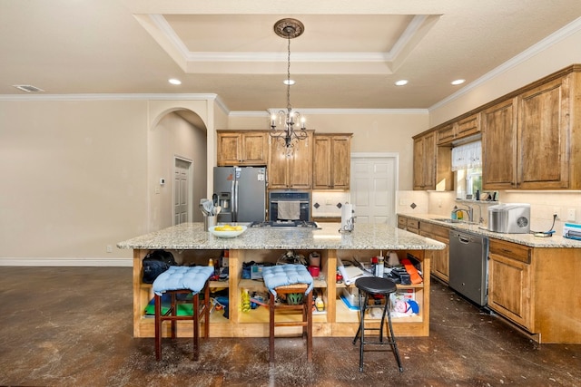 kitchen featuring light stone counters, a kitchen island, stainless steel appliances, a tray ceiling, and crown molding