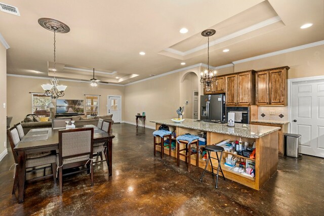 kitchen with ceiling fan with notable chandelier, appliances with stainless steel finishes, and a raised ceiling