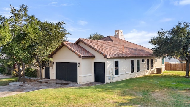 exterior space featuring a tile roof, stucco siding, a lawn, an attached garage, and fence