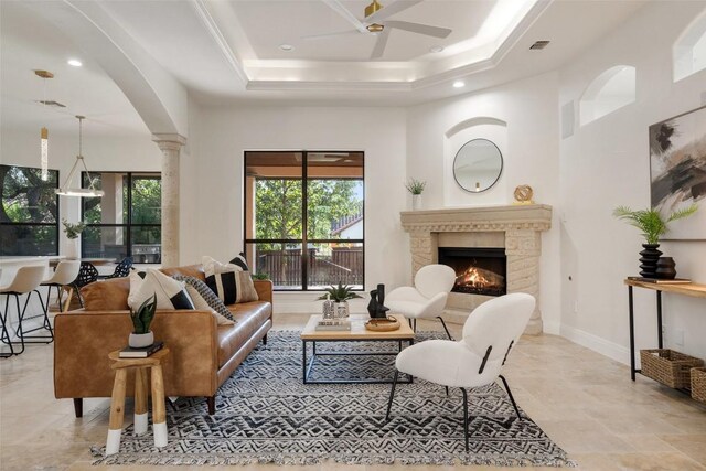 living room featuring a raised ceiling, ornate columns, and ceiling fan