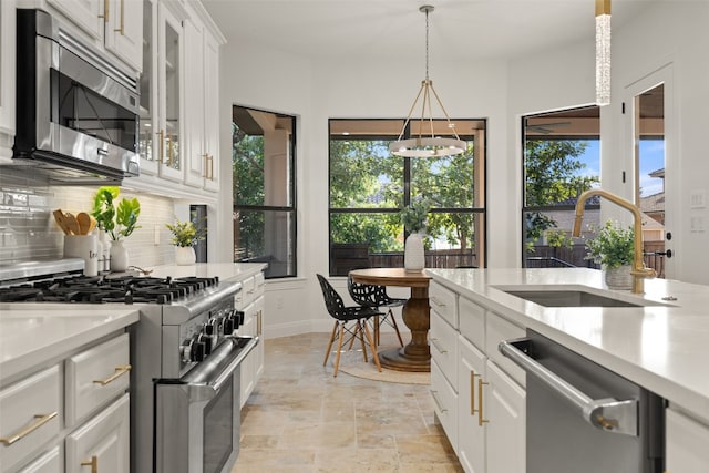 kitchen featuring white cabinets, glass insert cabinets, appliances with stainless steel finishes, light countertops, and a sink