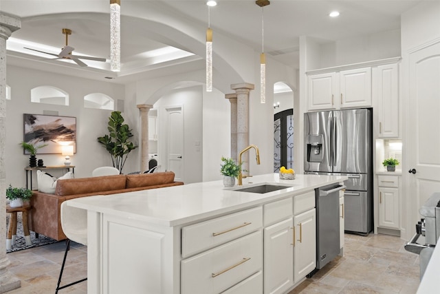 kitchen featuring ornate columns, white cabinetry, sink, a center island with sink, and appliances with stainless steel finishes