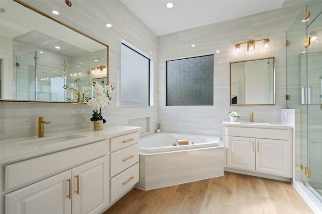 bathroom with hardwood / wood-style floors, vanity, shower with separate bathtub, and tile walls