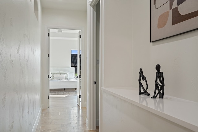 hall featuring baseboards and stone tile floors