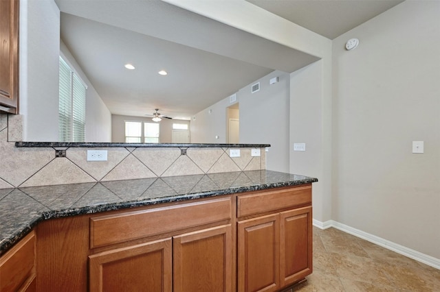 kitchen with dark stone countertops, ceiling fan, and tasteful backsplash