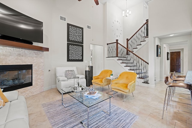 living room with a notable chandelier, a fireplace, and a towering ceiling