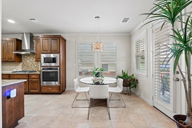 kitchen featuring wall chimney exhaust hood, a chandelier, pendant lighting, tasteful backsplash, and appliances with stainless steel finishes