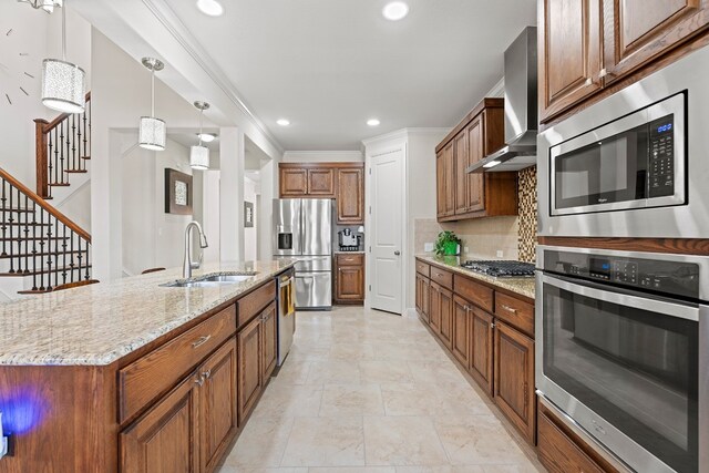 kitchen featuring light stone counters, sink, a kitchen island with sink, wall chimney exhaust hood, and stainless steel appliances