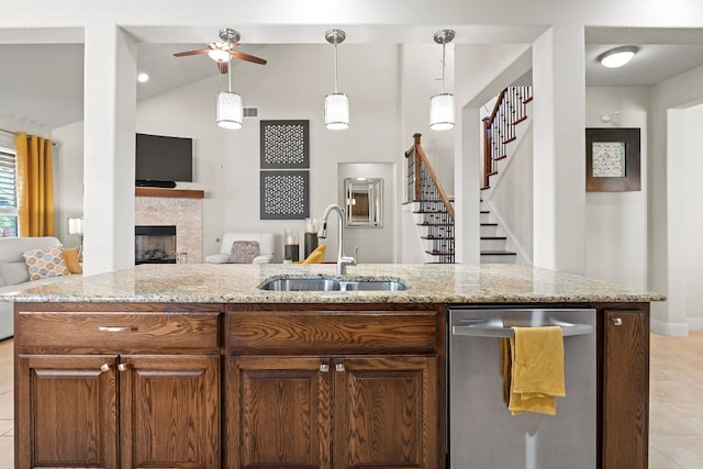 kitchen with light tile patterned flooring, hanging light fixtures, sink, dishwasher, and a fireplace