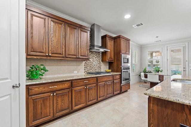 kitchen with wall chimney exhaust hood, tasteful backsplash, crown molding, light stone counters, and stainless steel appliances