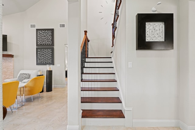 stairs with high vaulted ceiling, baseboards, and visible vents