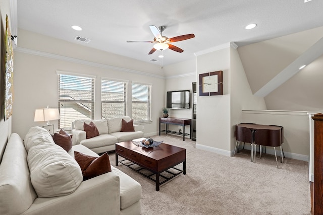 living room with ornamental molding, light carpet, ceiling fan, and a textured ceiling