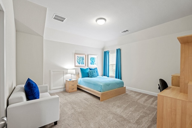 bedroom with light colored carpet and a textured ceiling