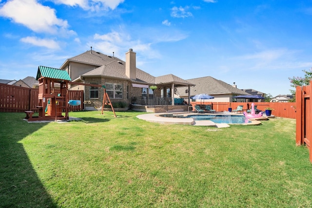 rear view of property featuring a fenced in pool, a fenced backyard, a playground, a chimney, and a lawn