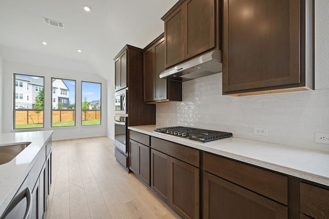 408 Ridgewell Loop, Georgetown, TX 78633 - kitchen featuring stainless steel appliances, under cabinet range hood, tasteful backsplash, light wood finished floors, and vaulted ceiling