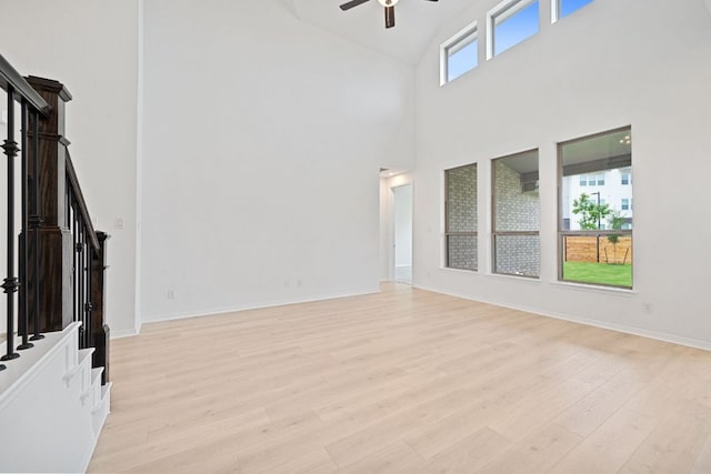 408 Ridgewell Loop, Georgetown, TX 78633 - unfurnished living room with high vaulted ceiling, ceiling fan, stairs, and light wood-type flooring