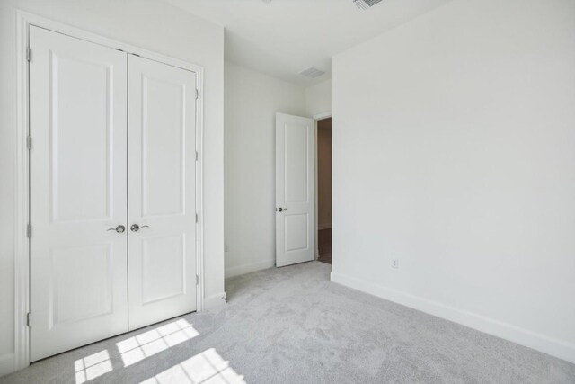 unfurnished bedroom featuring a closet and light colored carpet