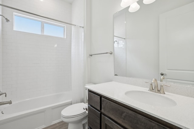 full bathroom featuring hardwood / wood-style flooring, tiled shower / bath combo, vanity, and toilet