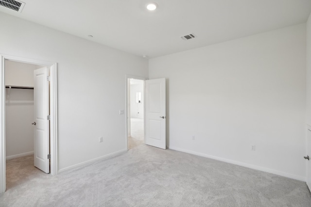 unfurnished bedroom featuring light carpet, a closet, and a spacious closet