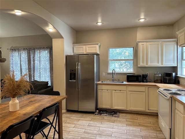 kitchen with white cabinets, sink, light hardwood / wood-style flooring, stainless steel fridge with ice dispenser, and white electric range