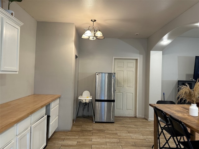 kitchen featuring light hardwood / wood-style floors, white cabinetry, wood counters, and pendant lighting