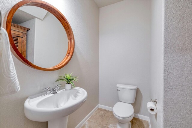 bathroom featuring toilet, sink, and tile patterned flooring