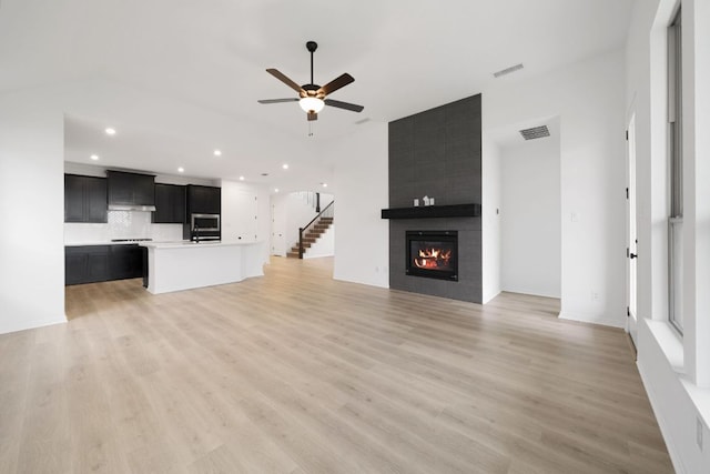 537 Raleigh Dr, Georgetown, TX 78633 - unfurnished living room with light wood-style floors, ceiling fan, recessed lighting, a large fireplace, and stairs