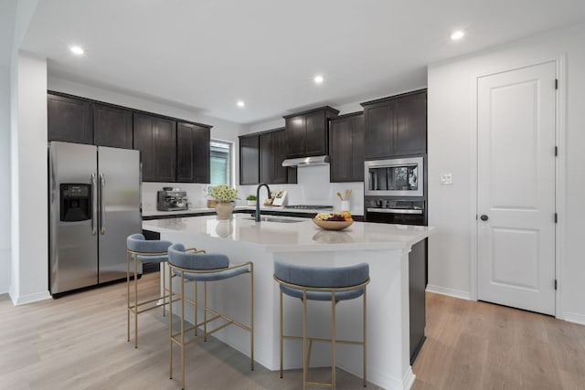 537 Raleigh Dr, Georgetown, TX 78633 - kitchen with stainless steel appliances, a breakfast bar, under cabinet range hood, light wood-style floors, and light countertops