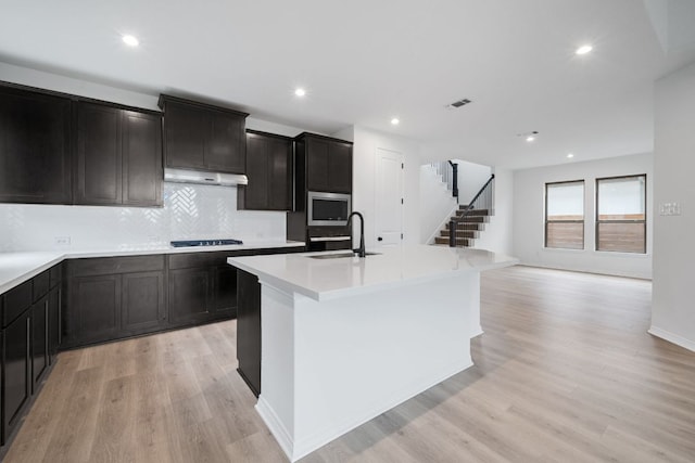 537 Raleigh Dr, Georgetown, TX 78633 - kitchen featuring a sink, under cabinet range hood, black cooktop, light wood-style floors, and recessed lighting