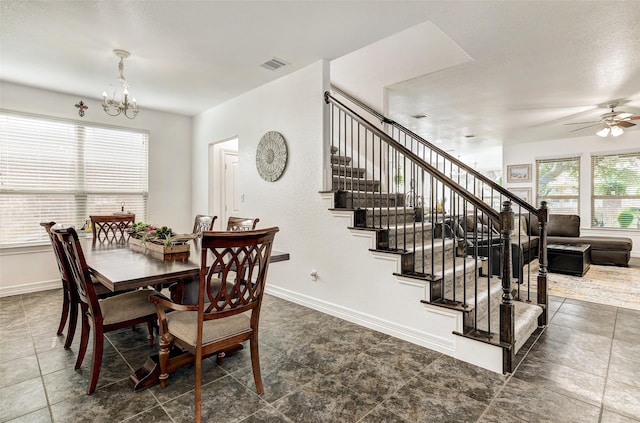 dining space with ceiling fan with notable chandelier