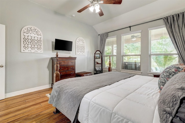 bedroom with vaulted ceiling, ceiling fan, hardwood / wood-style flooring, and multiple windows