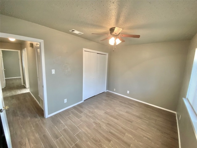 unfurnished bedroom featuring hardwood / wood-style floors, ceiling fan, a textured ceiling, and a closet