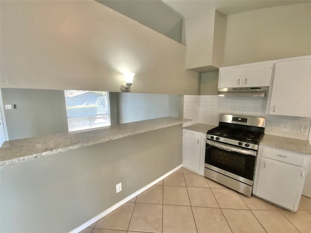 kitchen with backsplash, stainless steel stove, light tile patterned floors, white cabinetry, and kitchen peninsula