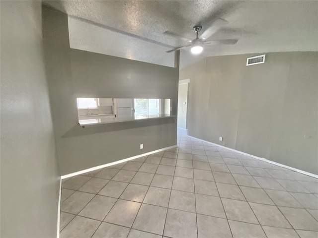 empty room featuring light tile patterned floors, a textured ceiling, ceiling fan, and lofted ceiling