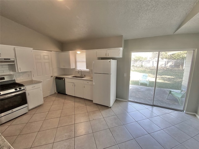 kitchen featuring stainless steel appliances, vaulted ceiling, exhaust hood, light tile patterned floors, and white cabinetry