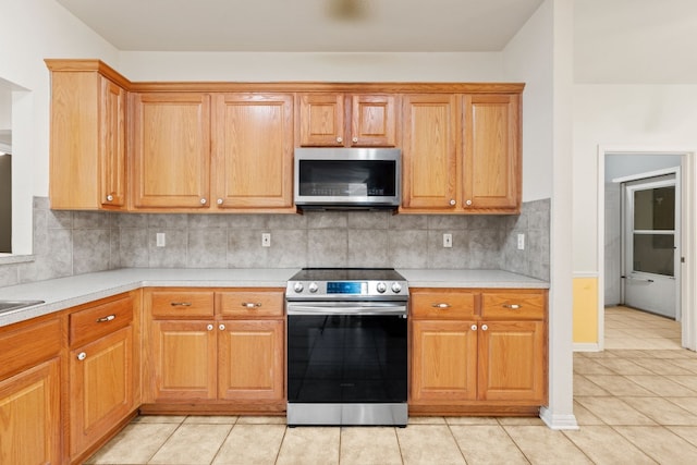 kitchen with stainless steel appliances, light tile patterned floors, and tasteful backsplash