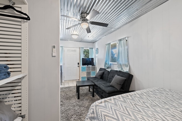 bedroom featuring wood-type flooring, wood walls, and ceiling fan