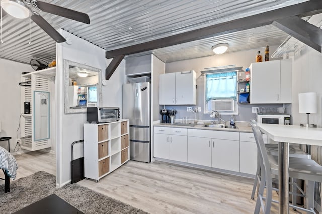 kitchen with light hardwood / wood-style floors, white cabinets, stainless steel refrigerator, ceiling fan, and sink