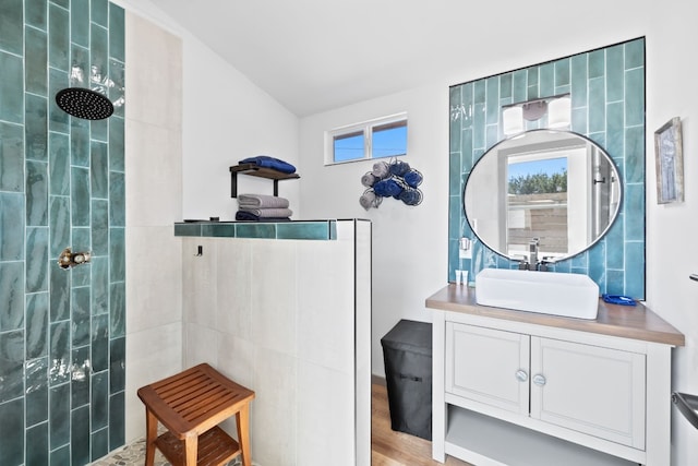 bathroom featuring vaulted ceiling, vanity, a tile shower, hardwood / wood-style flooring, and toilet