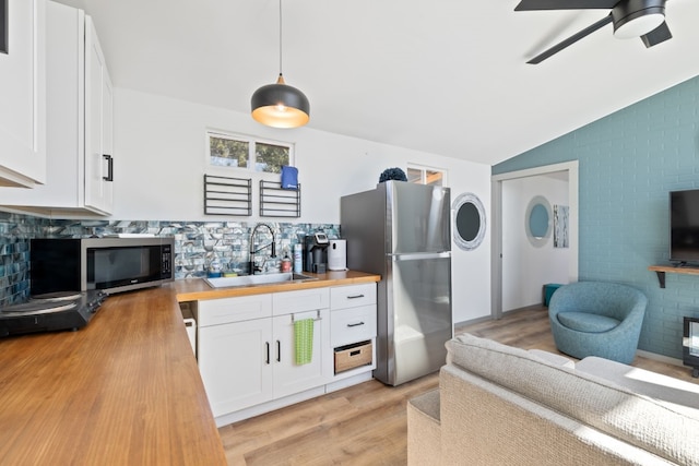 kitchen featuring hanging light fixtures, sink, white cabinetry, appliances with stainless steel finishes, and wood counters