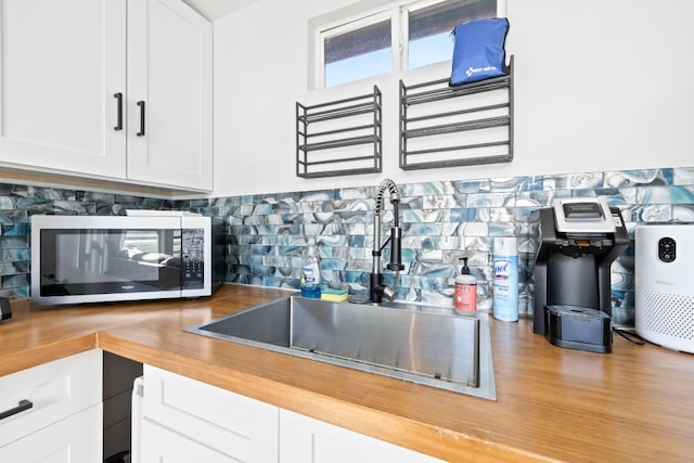 kitchen featuring backsplash, white cabinetry, light hardwood / wood-style floors, and sink