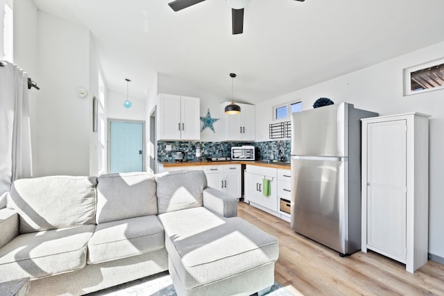 kitchen with appliances with stainless steel finishes, white cabinetry, pendant lighting, wooden counters, and ceiling fan