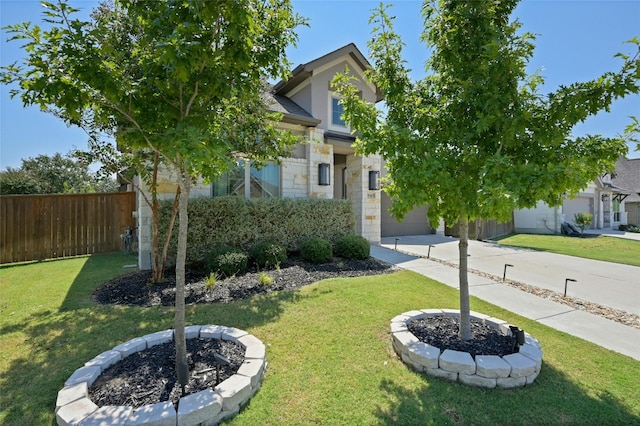 view of property hidden behind natural elements with a garage, a front lawn, and an outdoor fire pit