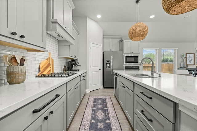 kitchen featuring sink, decorative light fixtures, light hardwood / wood-style flooring, stainless steel appliances, and decorative backsplash