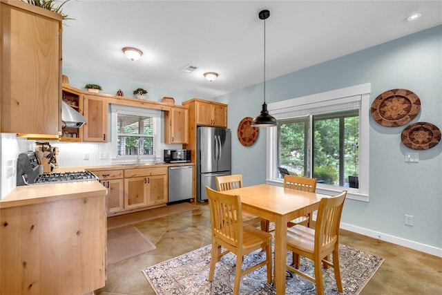 kitchen with ventilation hood, light brown cabinetry, appliances with stainless steel finishes, and hanging light fixtures